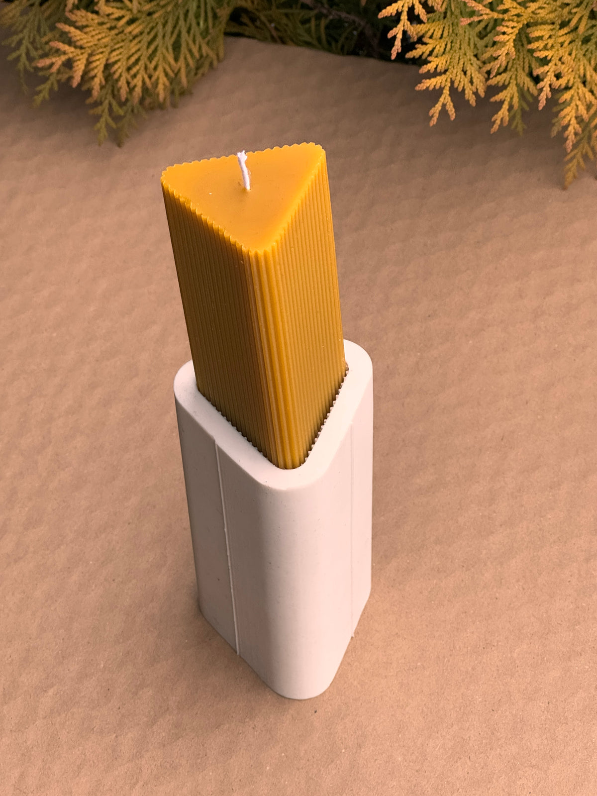Triangle Fluted Pillar beeswax candle being pushed out of its triangular silicone mould
