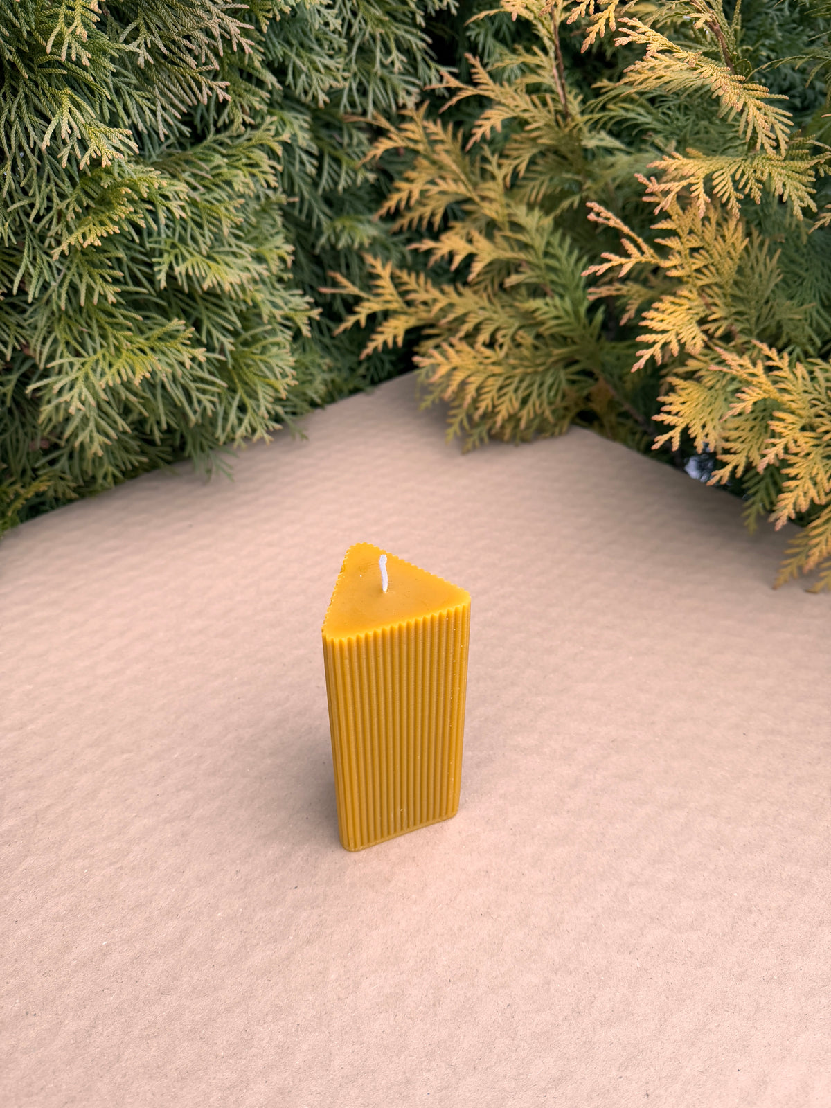 Triangle Fluted Pillar beeswax candle at a corner angle showing its three-sided shape