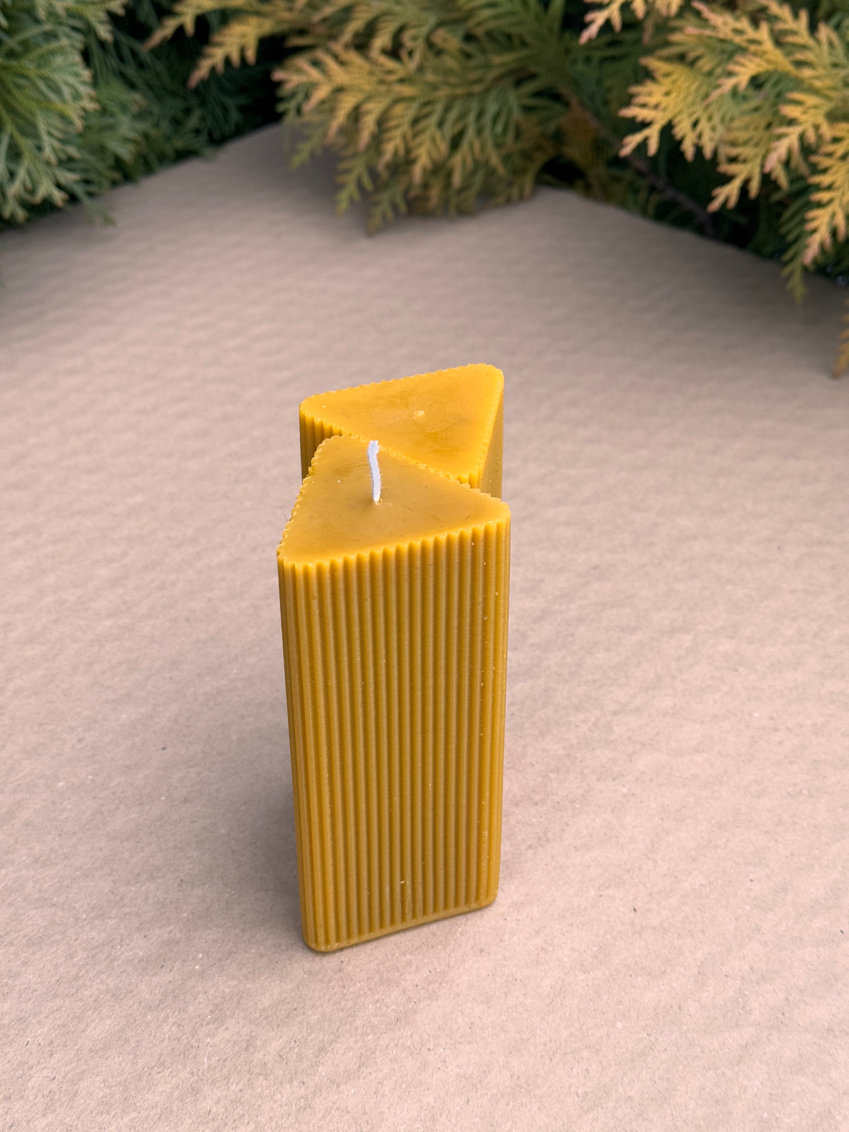 Two Triangle Fluted Pillar candles stacked at angles to show the triangular top and ribbed sides