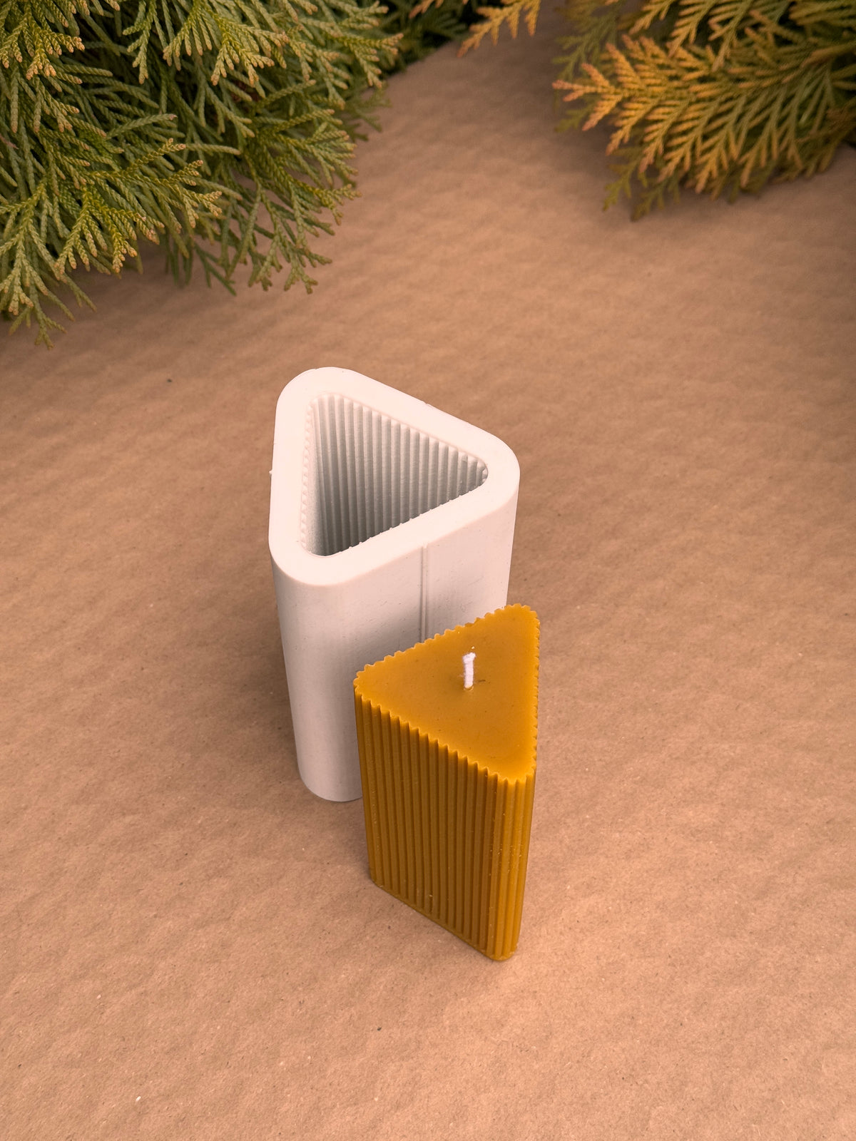 Triangle Fluted Pillar candle beside its upright triangular silicone mould showing the ribbed inside