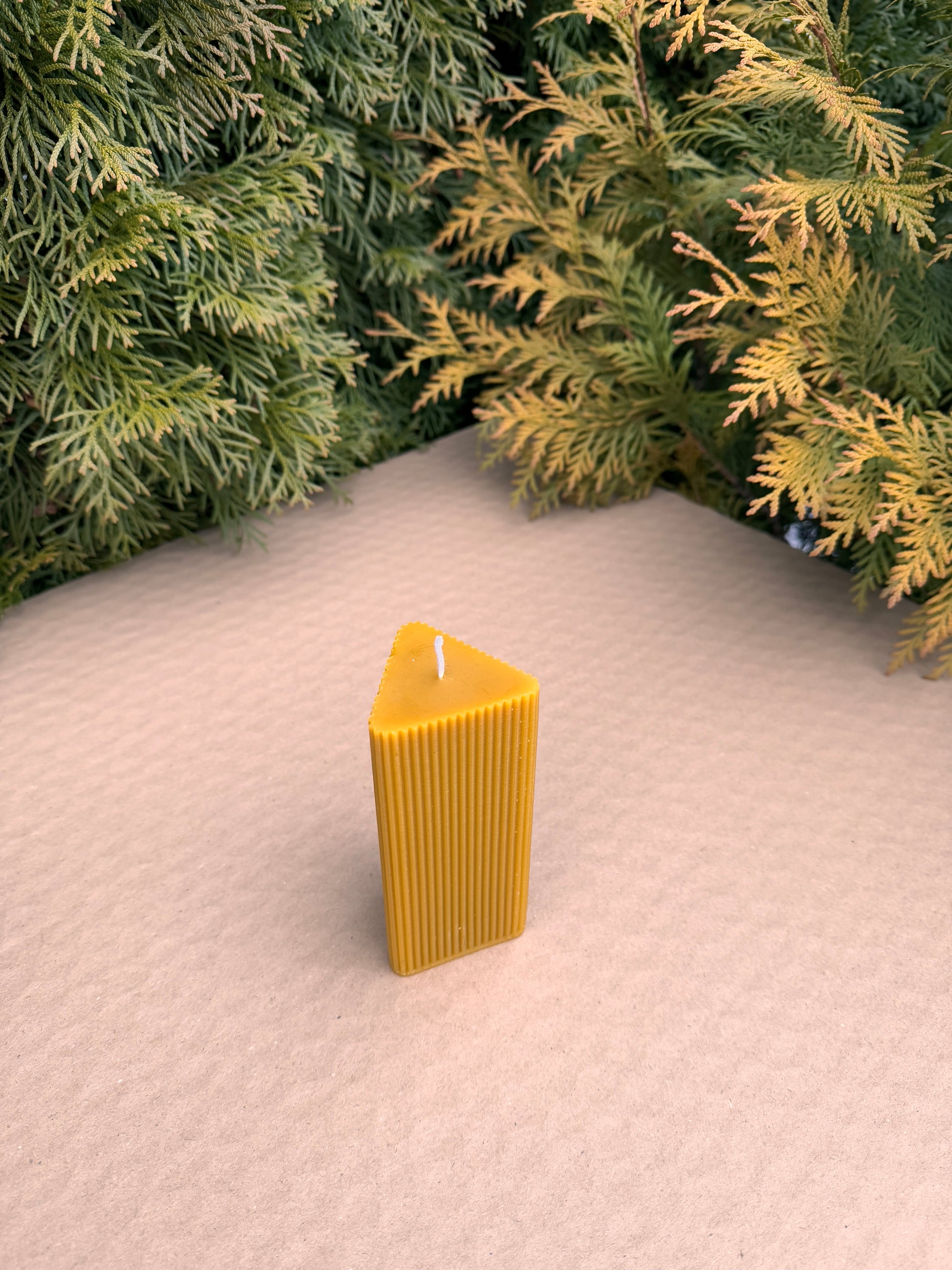 Side view of triangular fluted beeswax candle