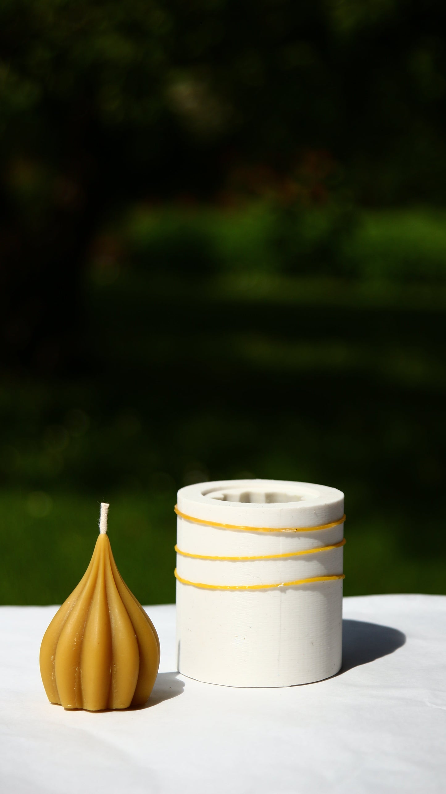 GARLIC silicone candle mold with two sizes and a garlic-shaped candle on a white surface outdoors