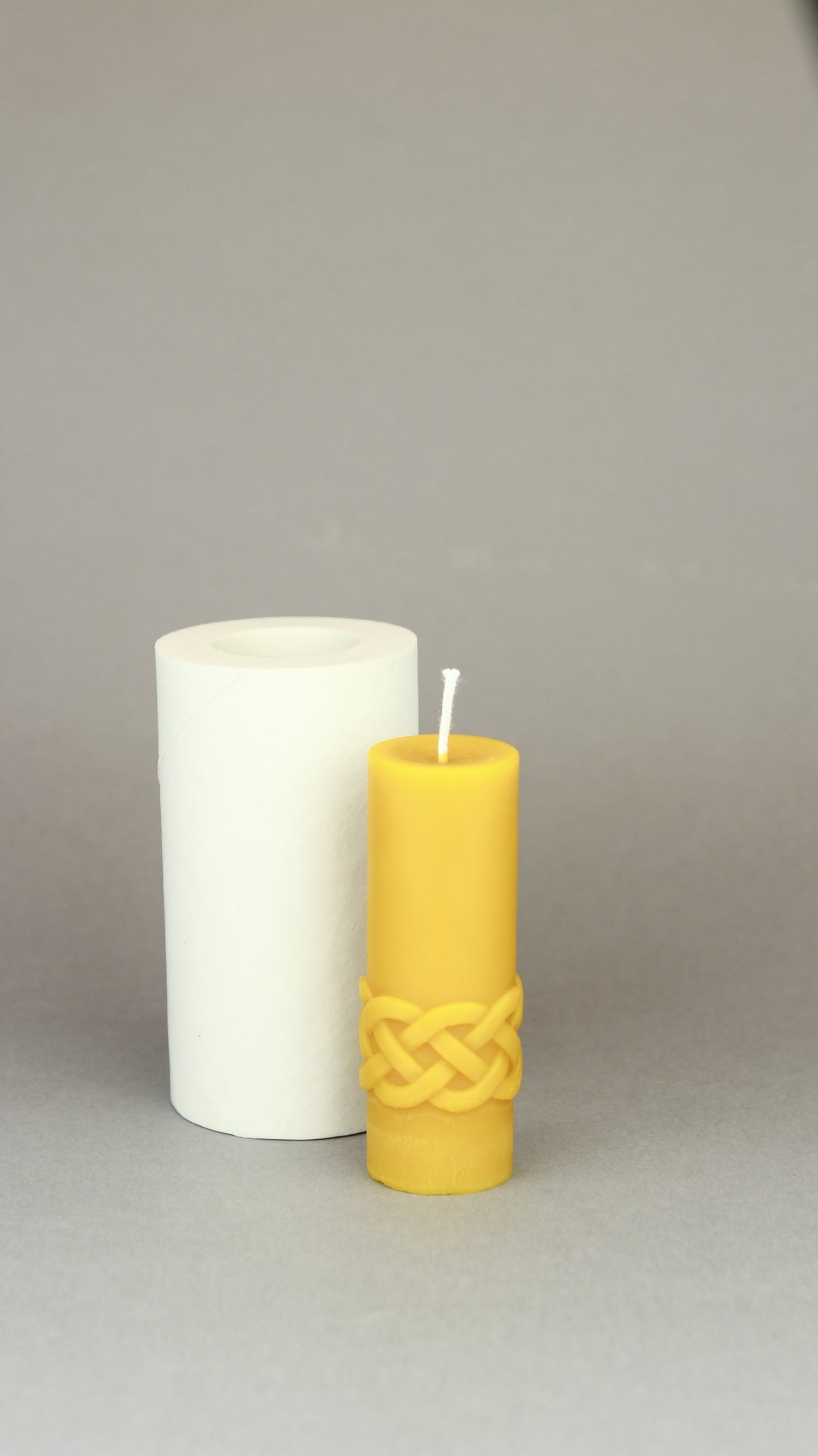 Karelia Motives beeswax pillar candle with patterned band next to its silicone mould