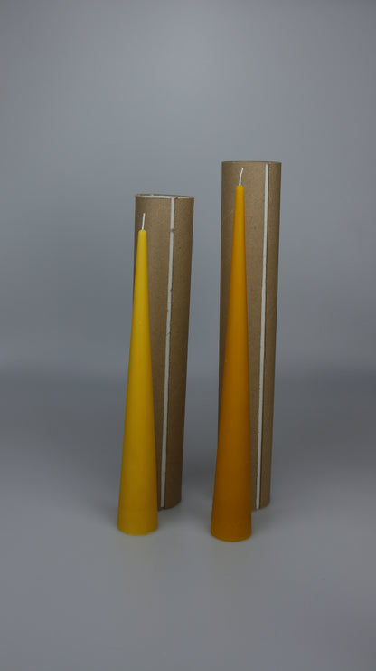 Two beeswax cone candles next to upright cardboard display tubes