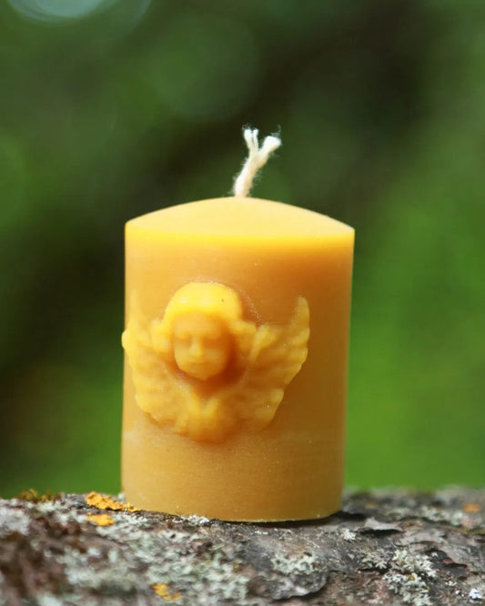 Beeswax candle with floral design on a textured surface with a blurred green background
